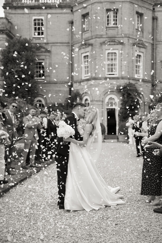 Wedding couple kissing outside under confetti